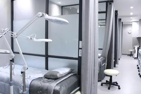 Day-care treatment bay with an examination couch, magnifying examination lamp and privacy curtains