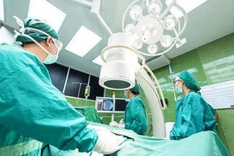 Surgical team in scrubs working under theatre lights in an operating room