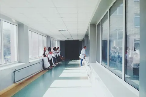 Clinical staff along a bright, window-lined hospital corridor